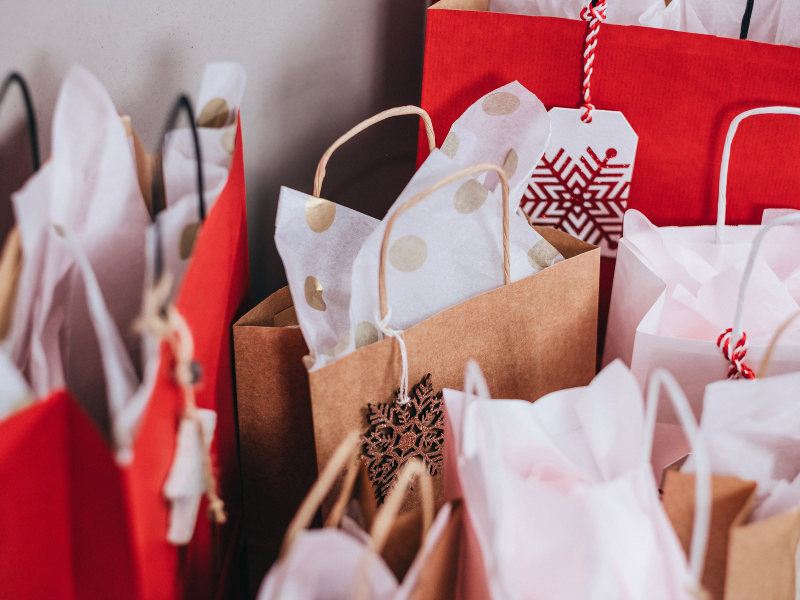 brown and red christmas bags stuffed with white gift wrap paper.